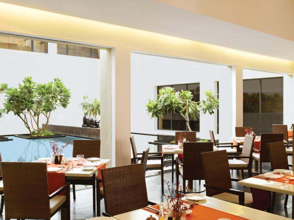 a restaurant with tables and chairs and large windows at Trident Chennai in Chennai