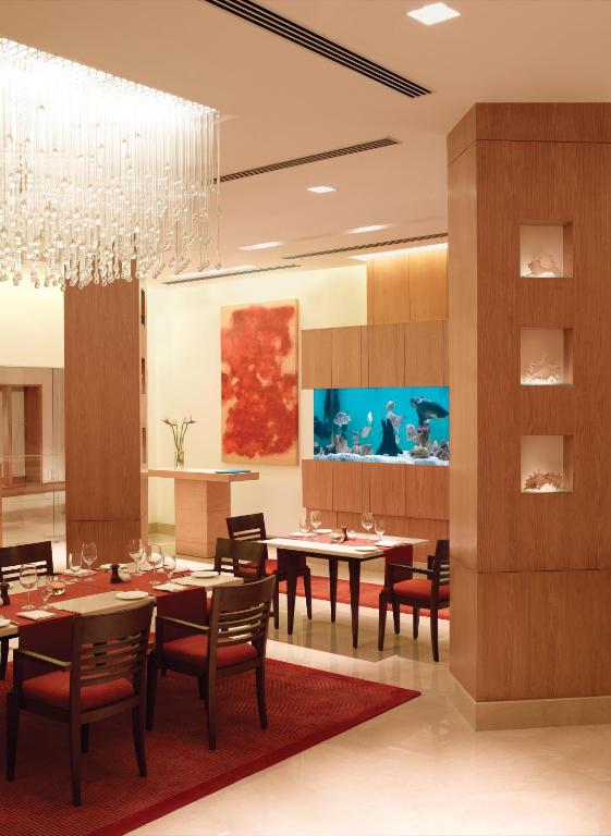 a dining room with tables and chairs and a chandelier at Trident Chennai in Chennai