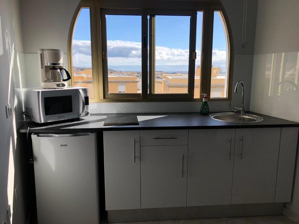 a kitchen with a microwave and a sink and a window at EXCELENTE Apto. 6 pax, TABLERO 12, cerca PLAYA DEL INGLES in El Tablero