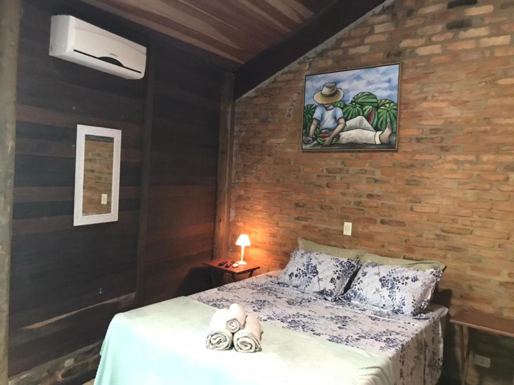 um quarto com uma cama e uma parede de tijolos em Vila da Pousadinha na Ilha do Mel