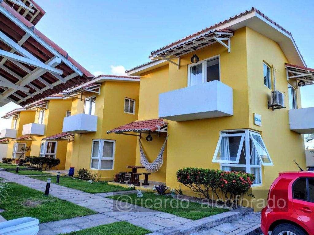 een geel huis met een rode auto ervoor geparkeerd bij Praia Bela Paraíba Casa 220 in Pitimbu