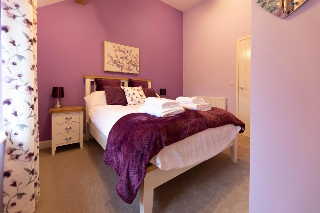 a bedroom with a bed with purple walls at Blodyn Cottage - Cosy, Self-Catering with Private Hot Tub in Bodfari