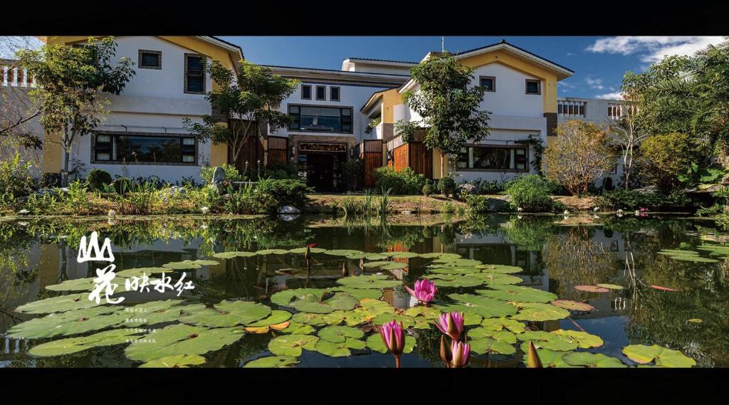 a pond with lilies in front of some buildings at 山花映水紅莊園民宿 in Yuemei