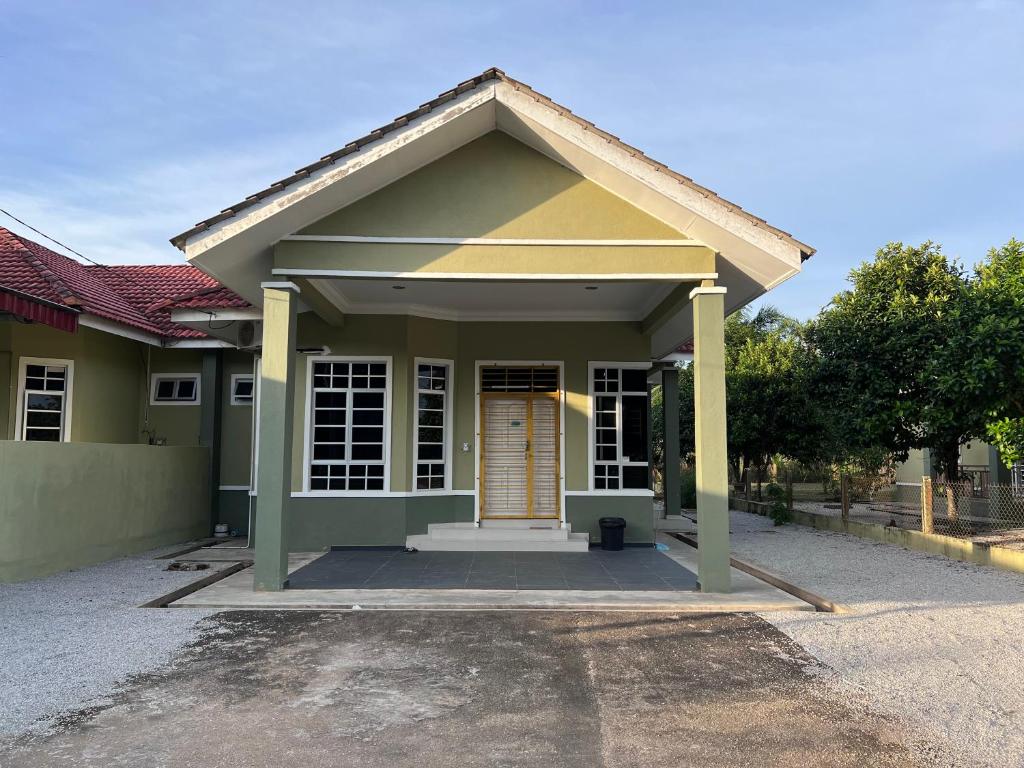 a small green house with a brown door at Teratak Anakanda in Kuala Berang