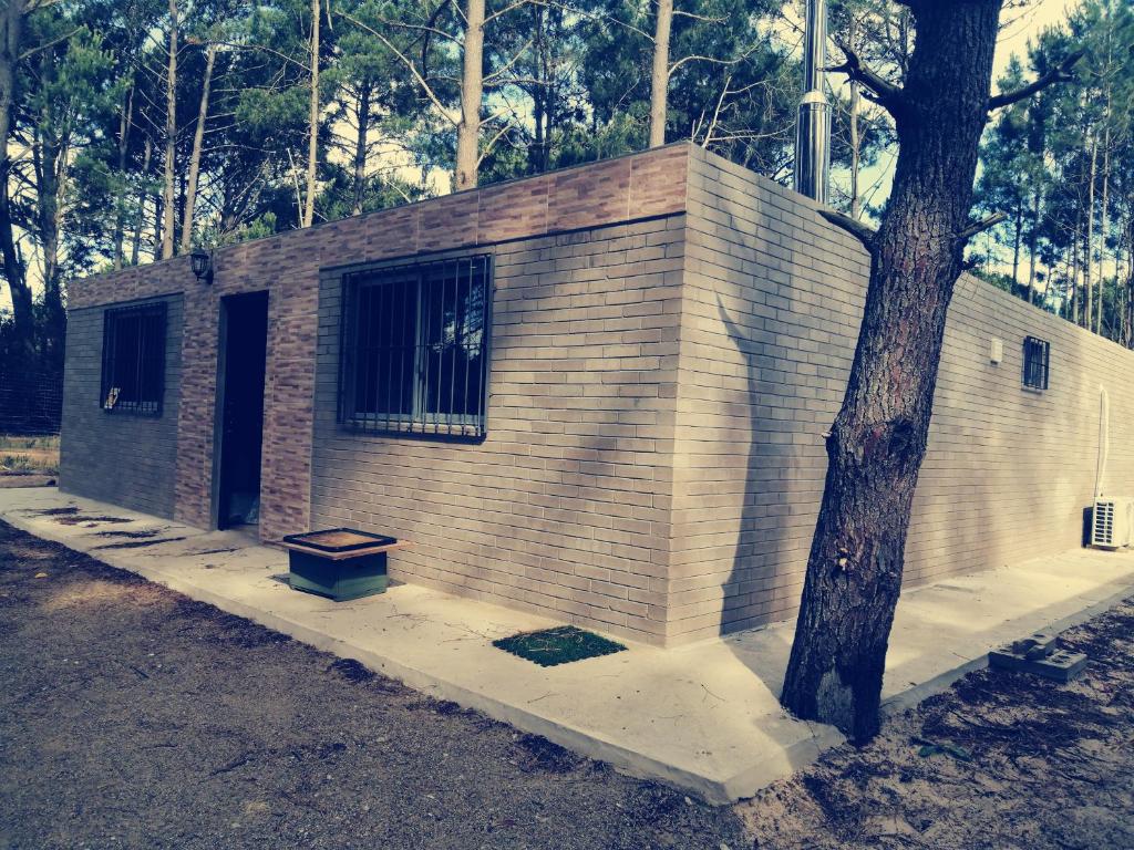 un edificio de ladrillo con un árbol delante de él en Casa en Jaureguiberry a 5 cuadras de la playa, en Jaureguiberry