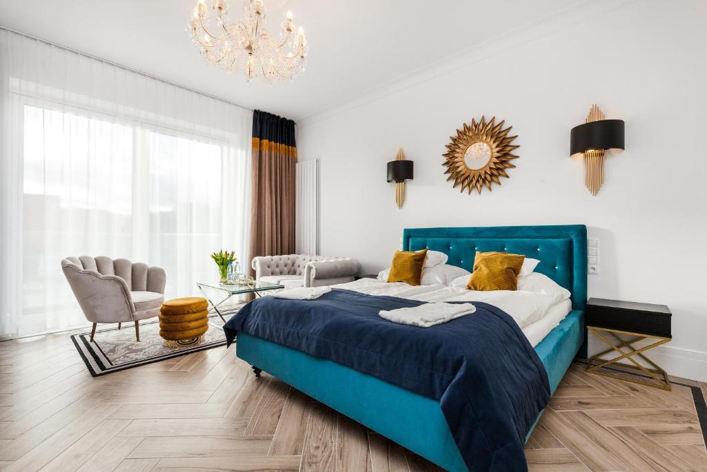 a bedroom with a blue bed and a chandelier at Prawdzic Family Resort & Wellness in Gdańsk