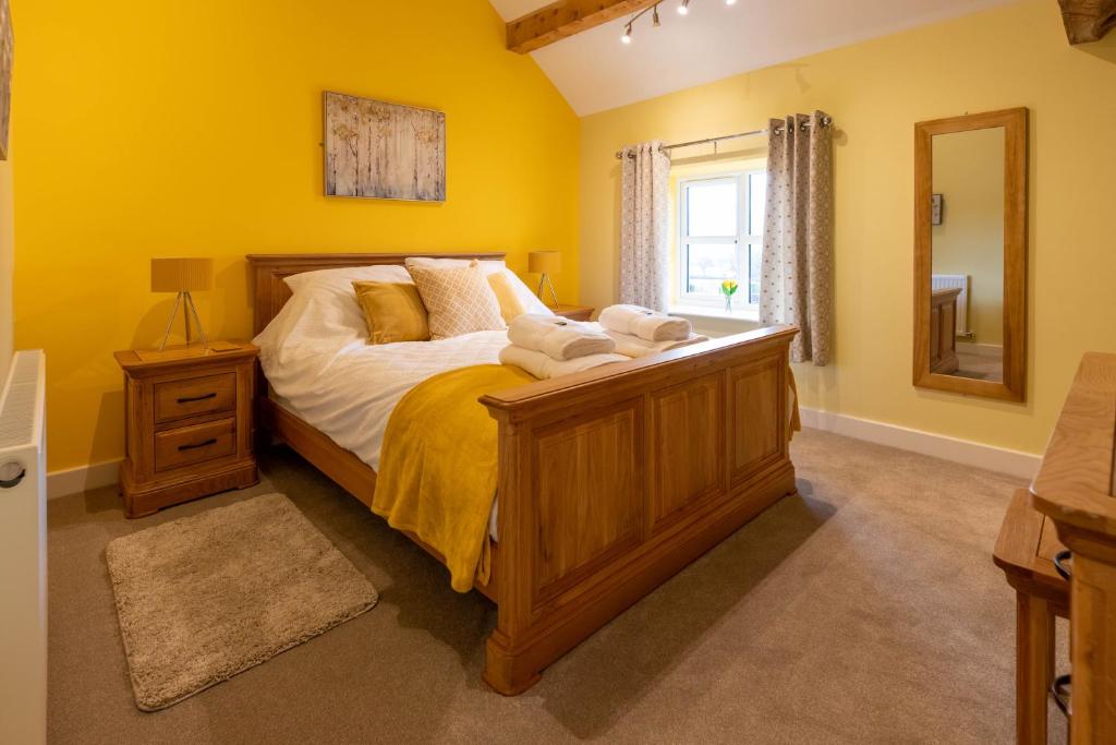 a bedroom with a large bed with yellow walls at Heulog Cottage - King Bed, Self-Catering with Private Hot Tub in Bodfari