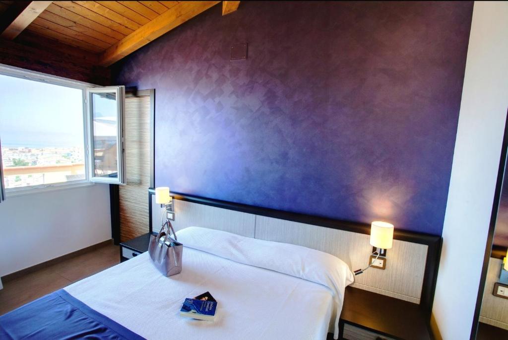 una camera con un letto bianco e una parete viola di Il Belvedere Guest House a Scalea