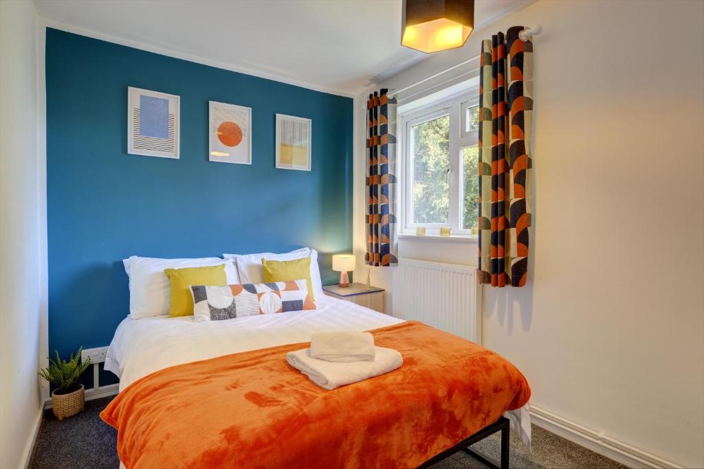 1 dormitorio con paredes azules y 1 cama con manta naranja en Inspire Homes 2-Bed Sleeps 5 near Leamington & M40 en Southam