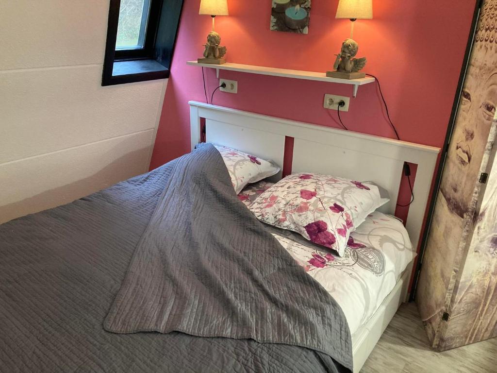 a bedroom with a bed with two lamps on the wall at cocon douillet avec chaleur ambiante du poêle à pellets in Hastière-par-delà