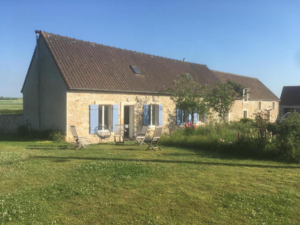 une maison en briques avec des chaises devant elle dans l'établissement La Roseaulière, à Bazinghen