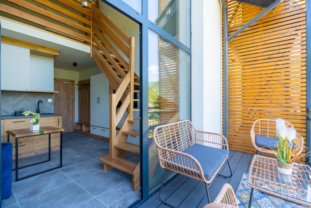 Small balcony with wicker chairs, table and wooden slat privacy screen, looking into living area.