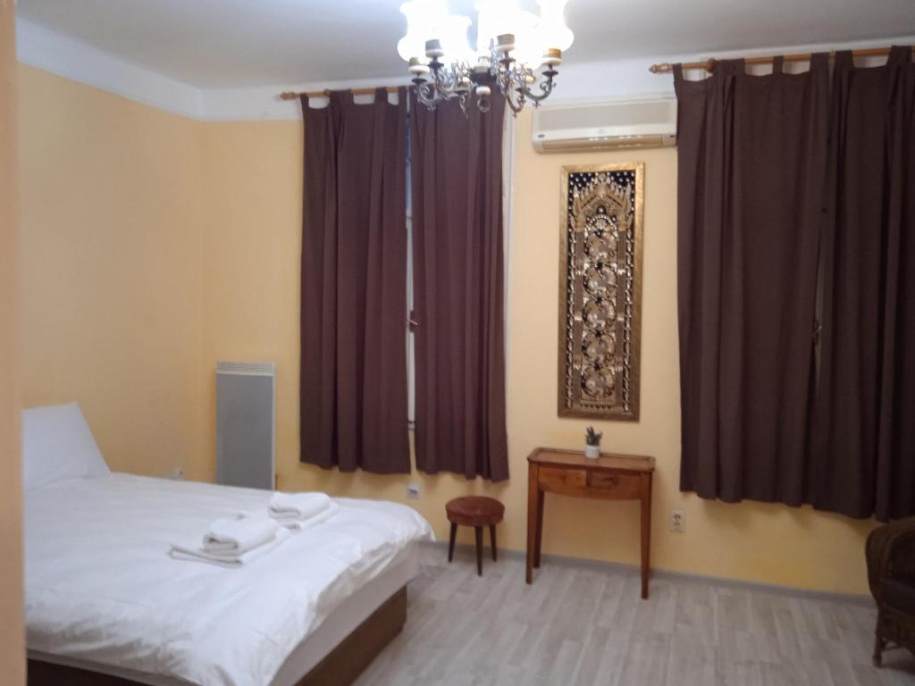 a bedroom with a bed and a table and curtains at Bajloni lux in Belgrade