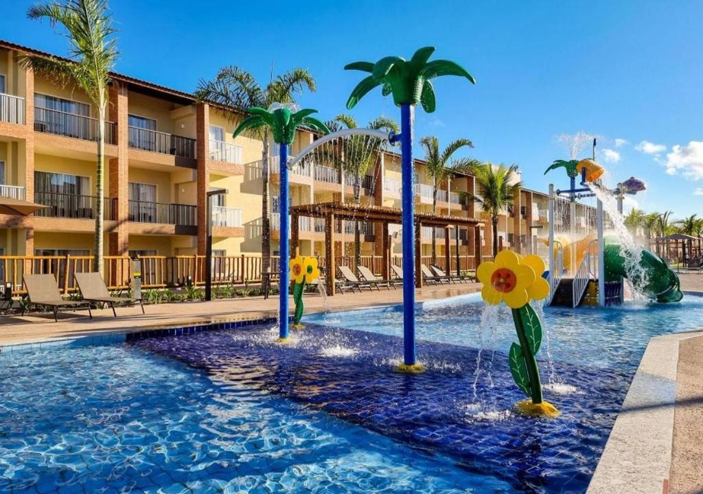 a pool at a resort with palm trees and a fountain at Ondas Praia Resort in Porto Seguro