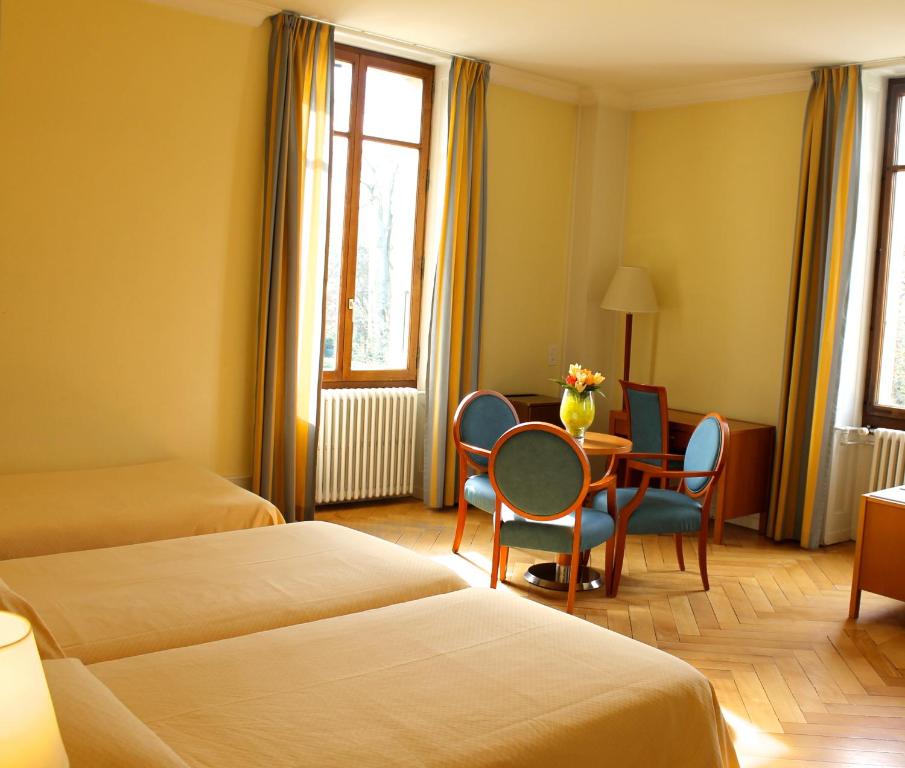 um quarto de hotel com duas camas e uma mesa e cadeiras em Le Cénacle em Genebra