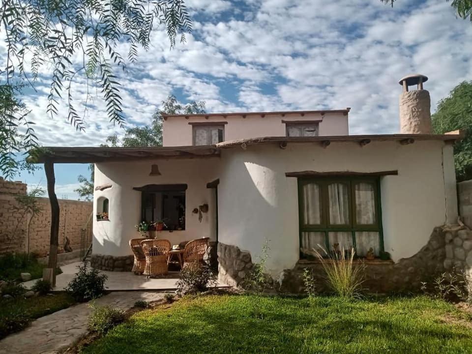 a small white house with a patio and grass at La Casa del Molle in San Carlos