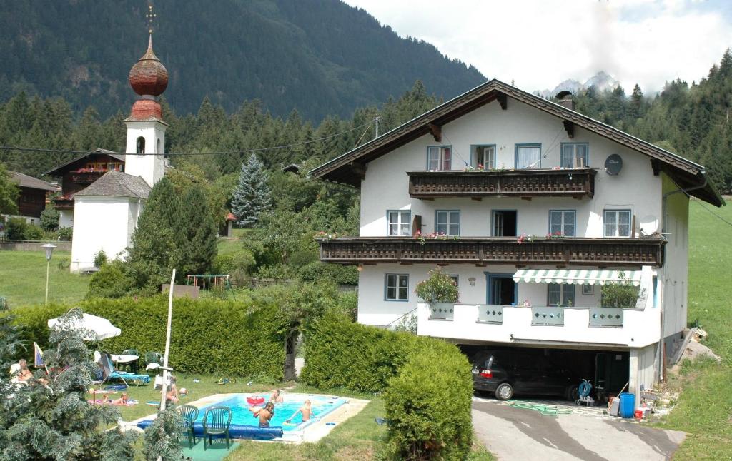 a building with a swimming pool next to a church at Casa da Honna in Matrei in Osttirol
