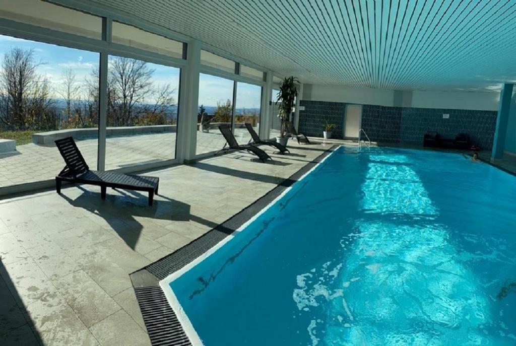 a large swimming pool with a chair in a building at Traumblick Bayerischer Wald, Pool & Sauna, Getränke, Klimaanlage in Freyung