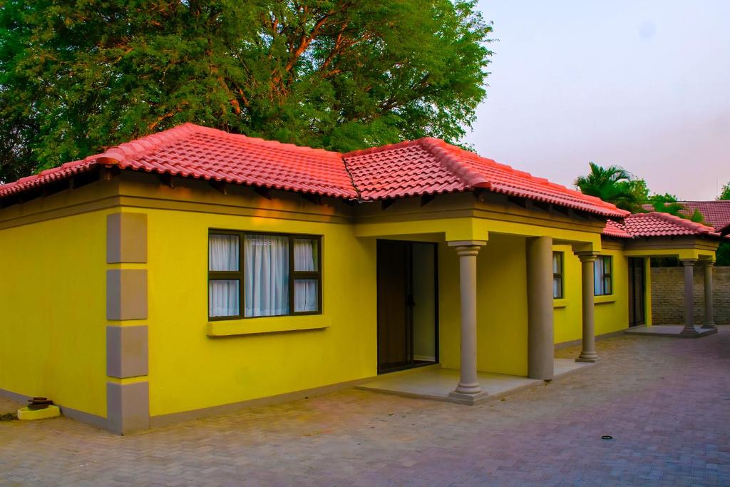 a small yellow house with a red roof at Maruleng Guest House in Hoedspruit
