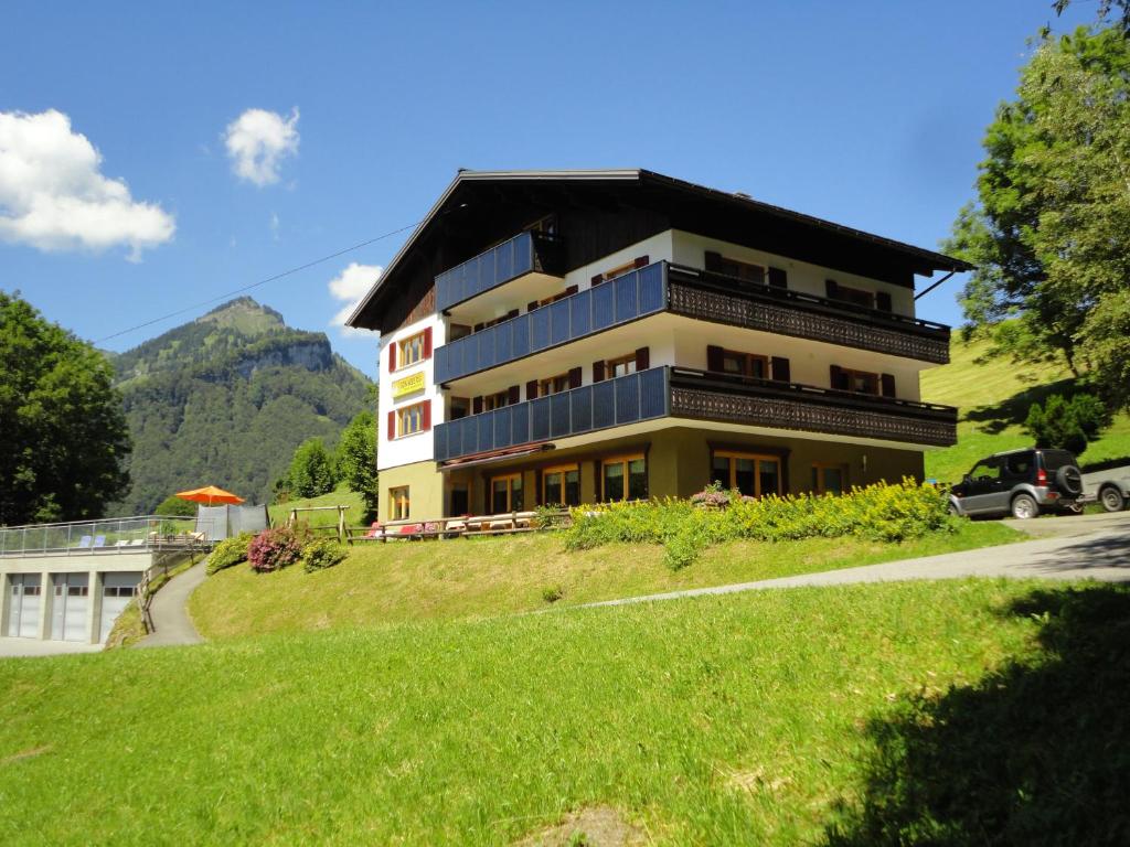 un edificio in cima a una collina con un campo verde di Haus Sonnberg a Mellau