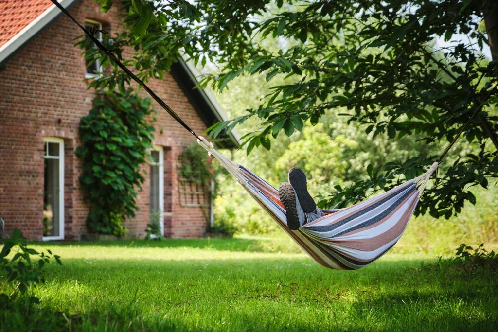 a person laying in a hammock in a yard at Landhäuschen Anderswo in Bocholt