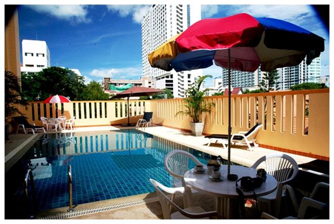 a swimming pool with a table and an umbrella at soi2inn in Pattaya Central