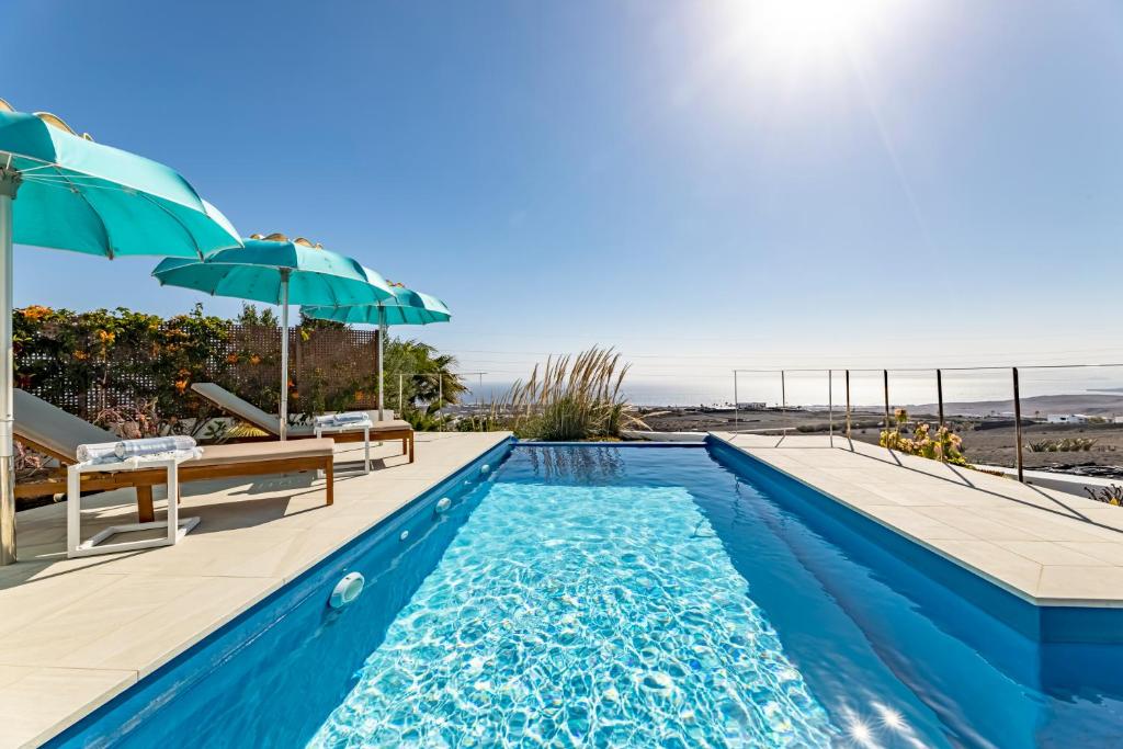 a swimming pool with an umbrella and a view of the beach at "NEW" Deluxe designer Villa Infinity, with Panoramic sea views,own exclusive heated private pool, subtropical gardens in Tías