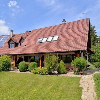 une grande maison avec un toit rouge et une cour dans l'établissement COTTAGE-GITE COEUR DE SUNDGAU, à Leymen
