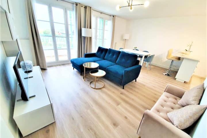 ein Wohnzimmer mit einem blauen Sofa und einem Tisch in der Unterkunft Sublime Appartemt 5 min Disneyland/Vallée Village/Val d'europe in Serris
