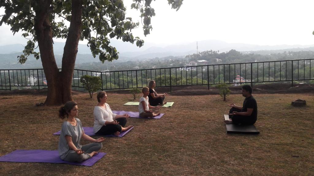a group of people sitting in the grass practicing yoga at Eco Village Yoga Home in Digana