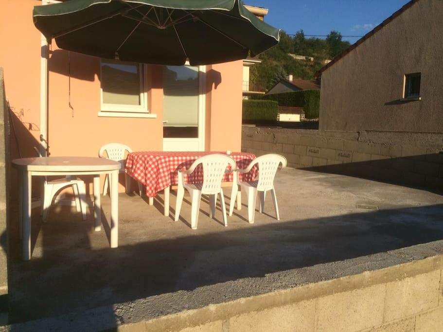 une table et des chaises avec une table et un parasol dans l'établissement Le Coin Tranquille au pied du Puy de Dôme, à Pontgibaud