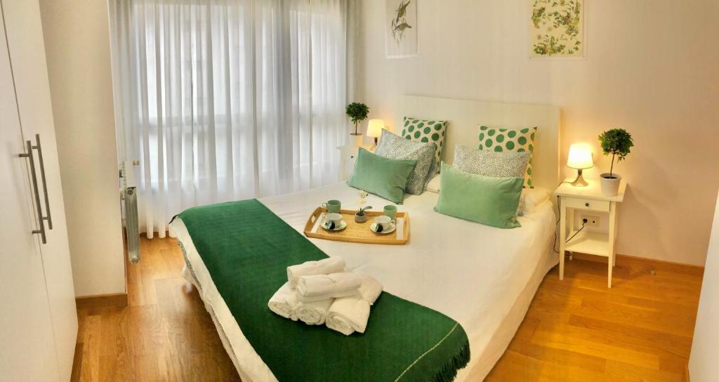 ein Schlafzimmer mit einem großen Bett mit grünen und weißen Kissen in der Unterkunft Apto2 Céntrico Frentebahía Garaje Incluido in Castro-Urdiales