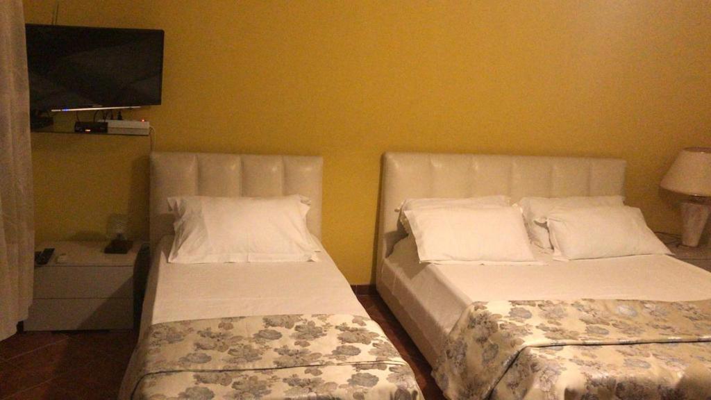 una camera da letto con due letti e una TV a schermo piatto di YELLOW ROOM a Durrës