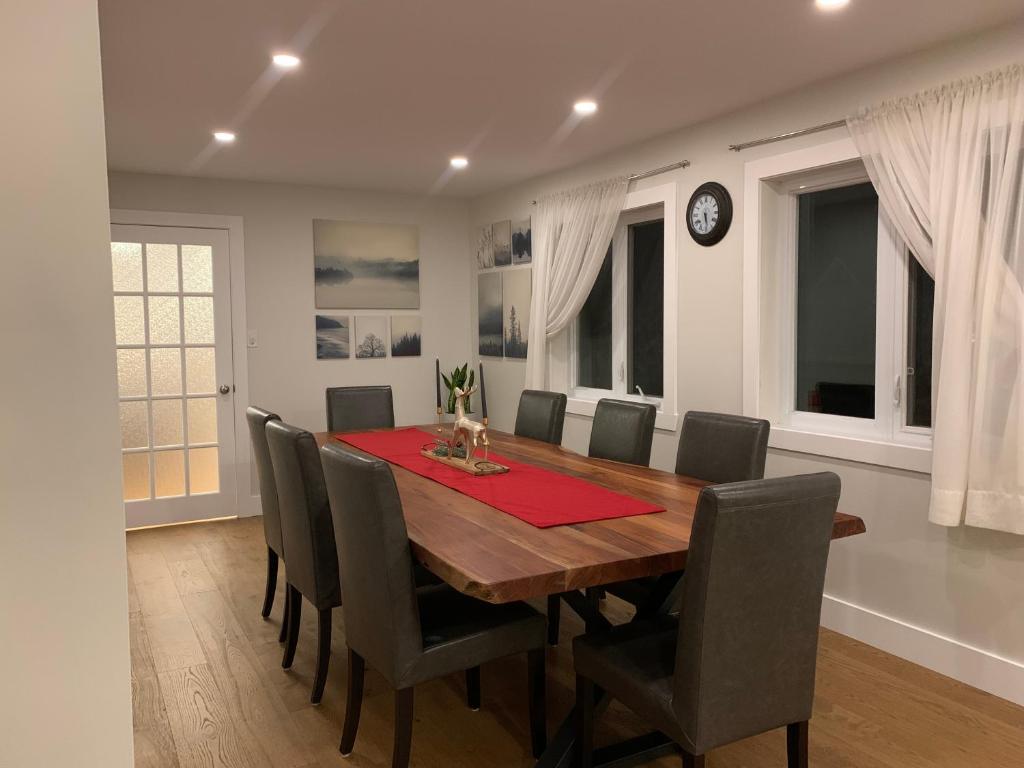 a dining room with a table and chairs and a clock at Le Pimbina in Mont-Tremblant