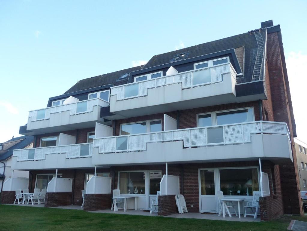 a building with white balconies and tables in front of it at Ferienwohnung Mare Nostrum 11 in Westerland