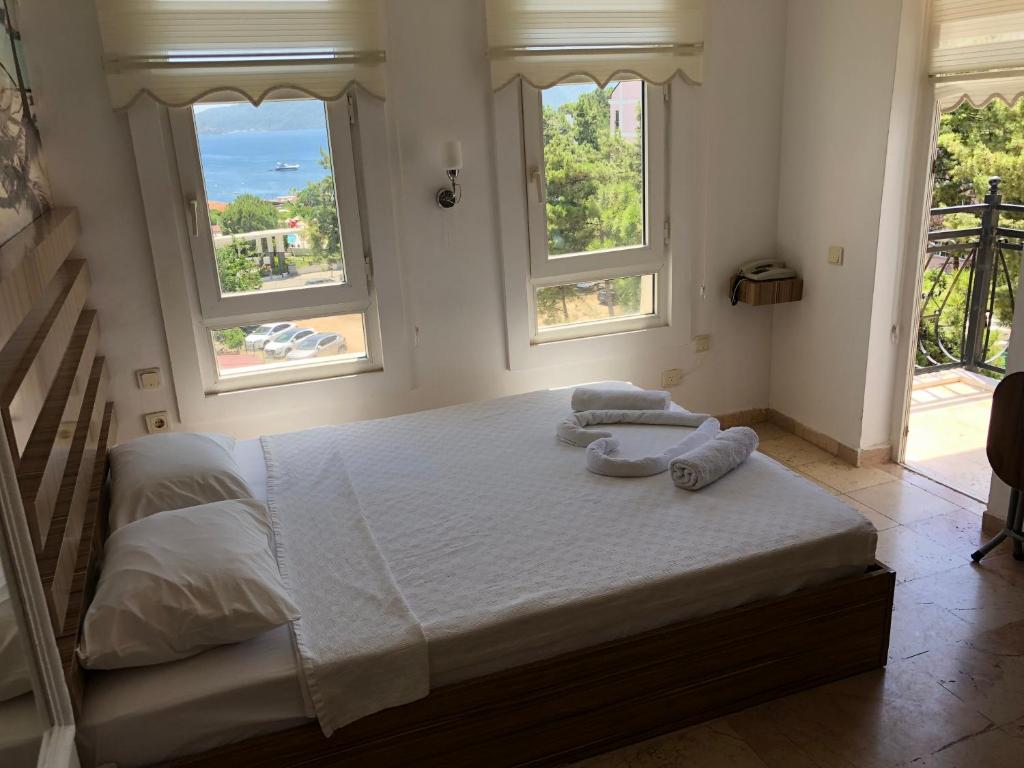 a bedroom with a large white bed with two windows at PEARL OF MARMARIS in Marmaris