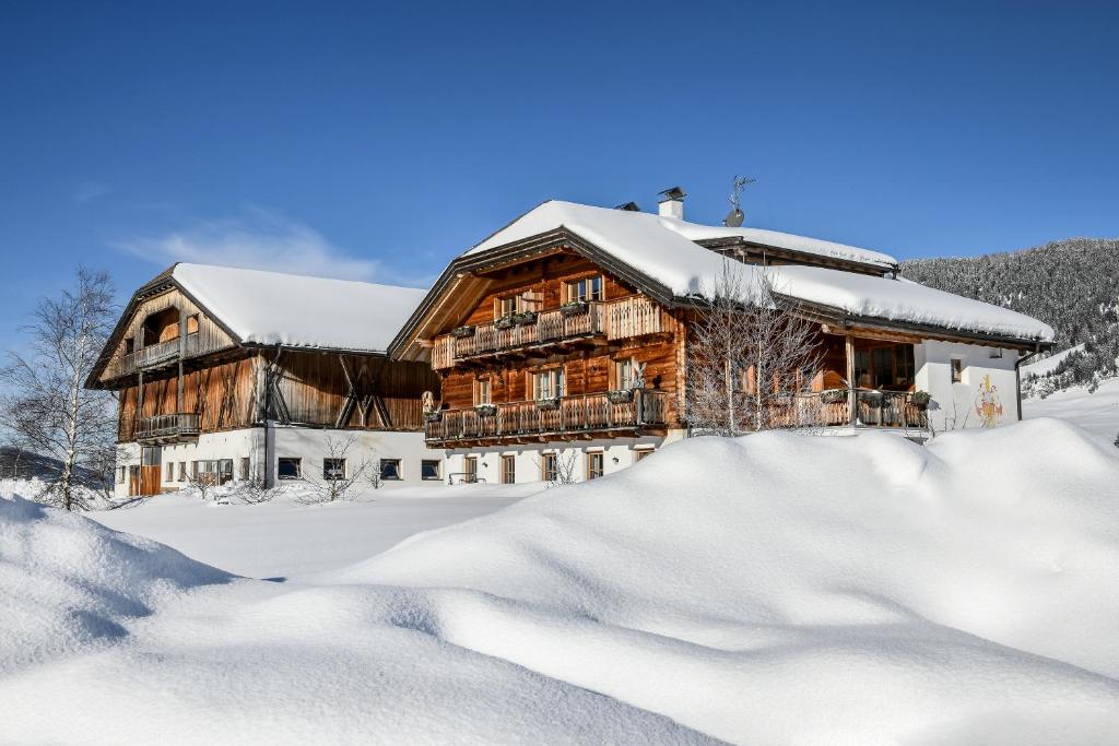 ein Blockhaus im Schnee mit Schnee in der Unterkunft Appartements Burgerhof in Toblach