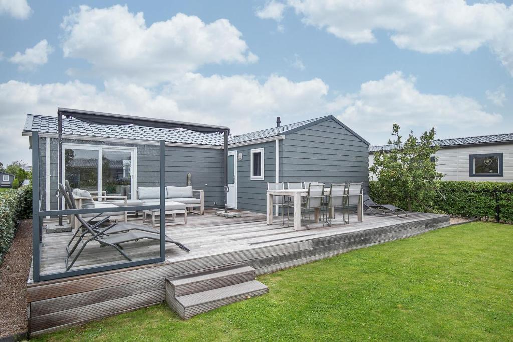 een terras met een tafel en stoelen en een huis bij Luxe Chalet Jara JS17 Oostkapelle in Oostkapelle