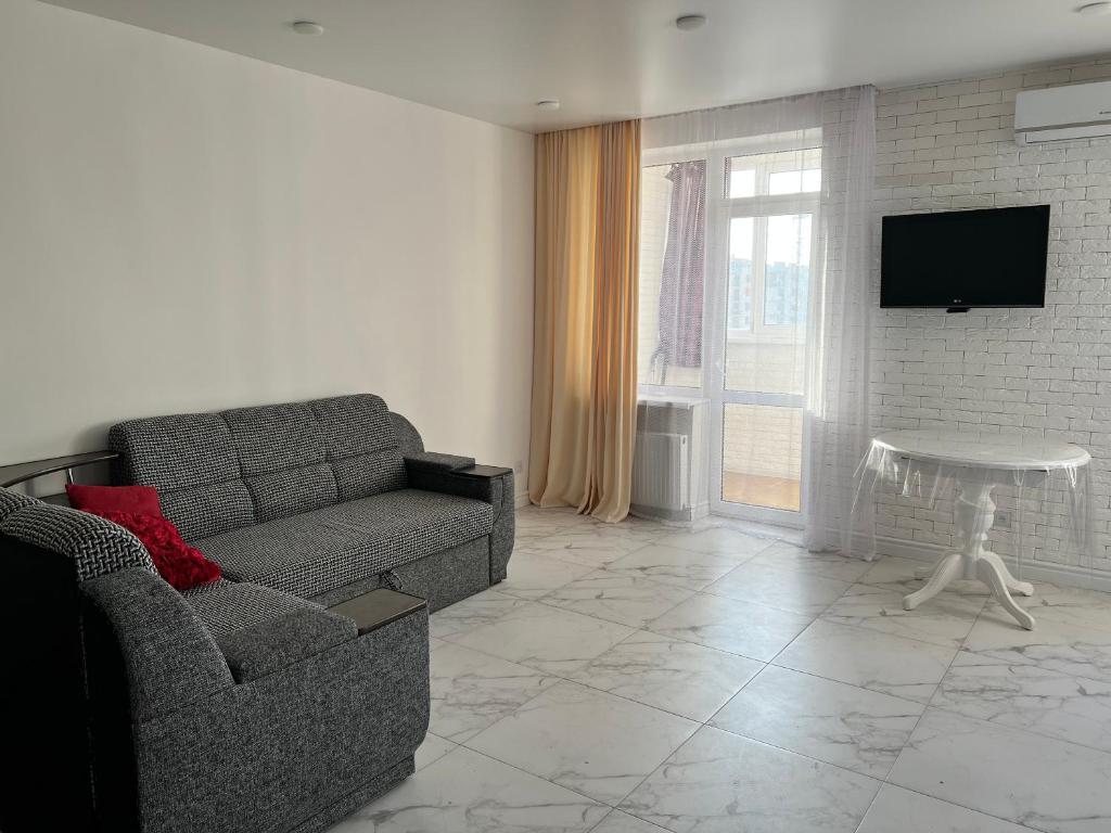 a living room with a couch and a tv at New Marine Apartment in Yuzhne