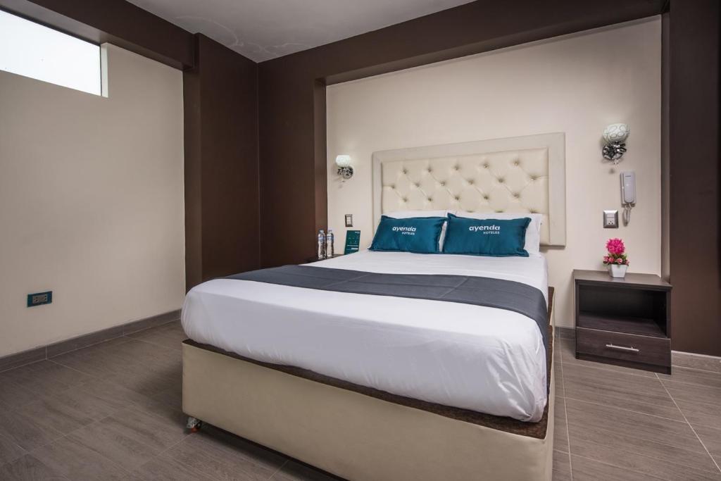 1 dormitorio con 1 cama grande con almohadas azules en Olimpo Hotel Sauna & Spa, en Cusco