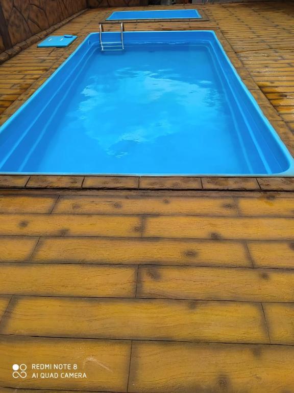 a large swimming pool with a wooden floor at Chácara Espaço Feliz in Olímpia