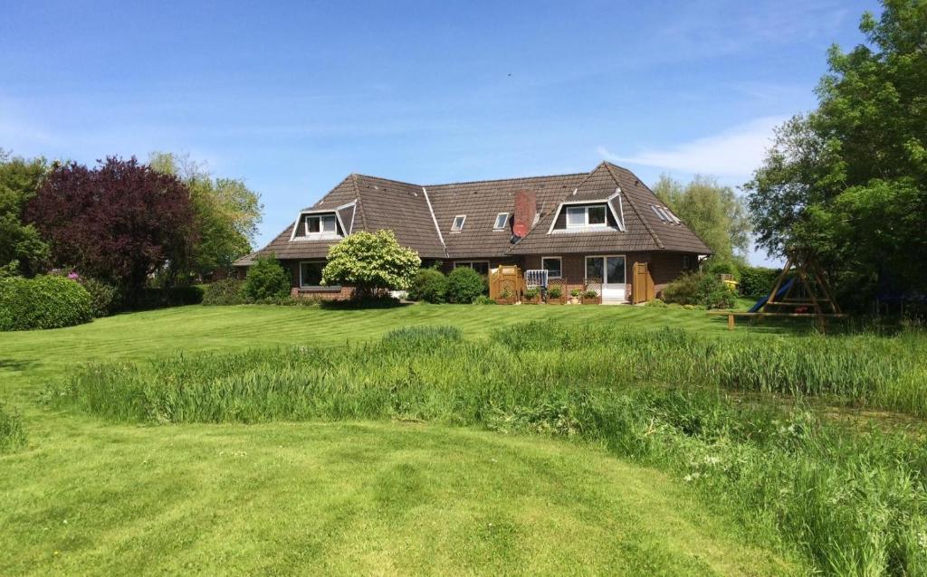 una casa en una colina con un patio verde en Tetenshof für Pferdeliebhaber, en Westerhever