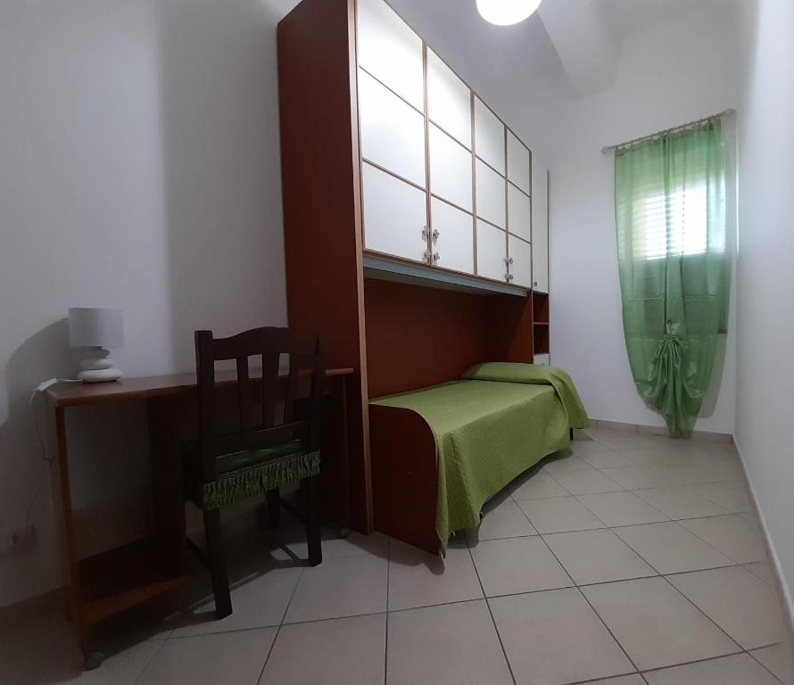 ein Schlafzimmer mit einem Bett, einem Stuhl und einem Schreibtisch in der Unterkunft Radici Blu intero alloggio in Siderno Marina
