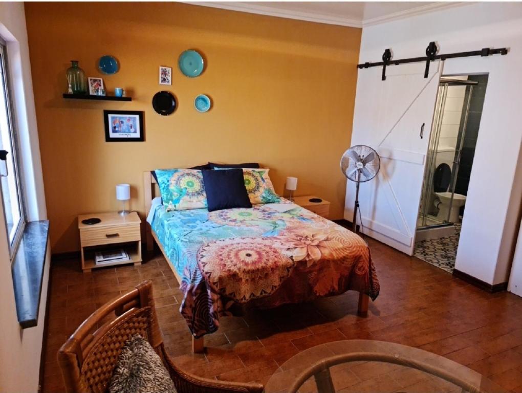 1 dormitorio con cama, mesa y ventilador en B&B "Villa Alegria", Tarrafal en Tarrafal