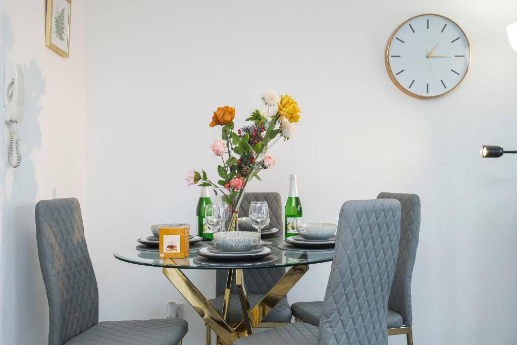 mesa de comedor con sillas y reloj en la pared en Lovely 2 bed Apartment with Parking in Thurrock, en South Ockendon