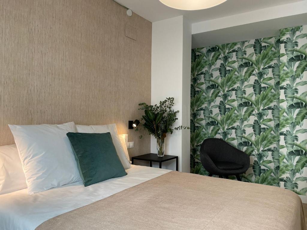 a bedroom with a bed with a green pillow and a chair at Apartamentos Cisneros in Alicante