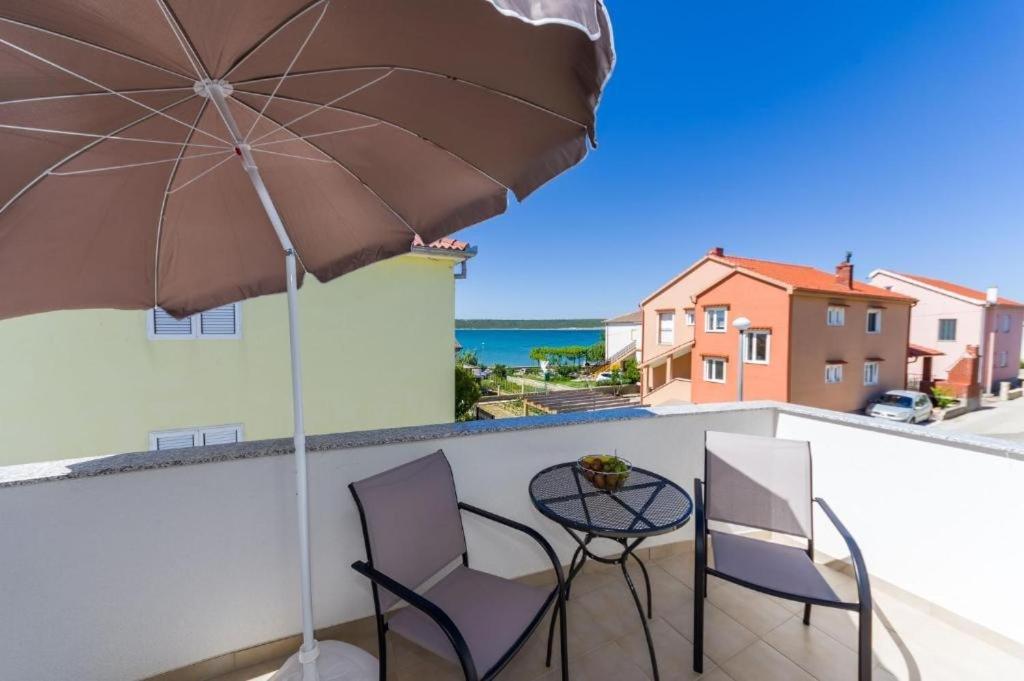 een patio met een tafel en stoelen en een parasol bij Apartments Ivanac - close to the beach in Ljubač