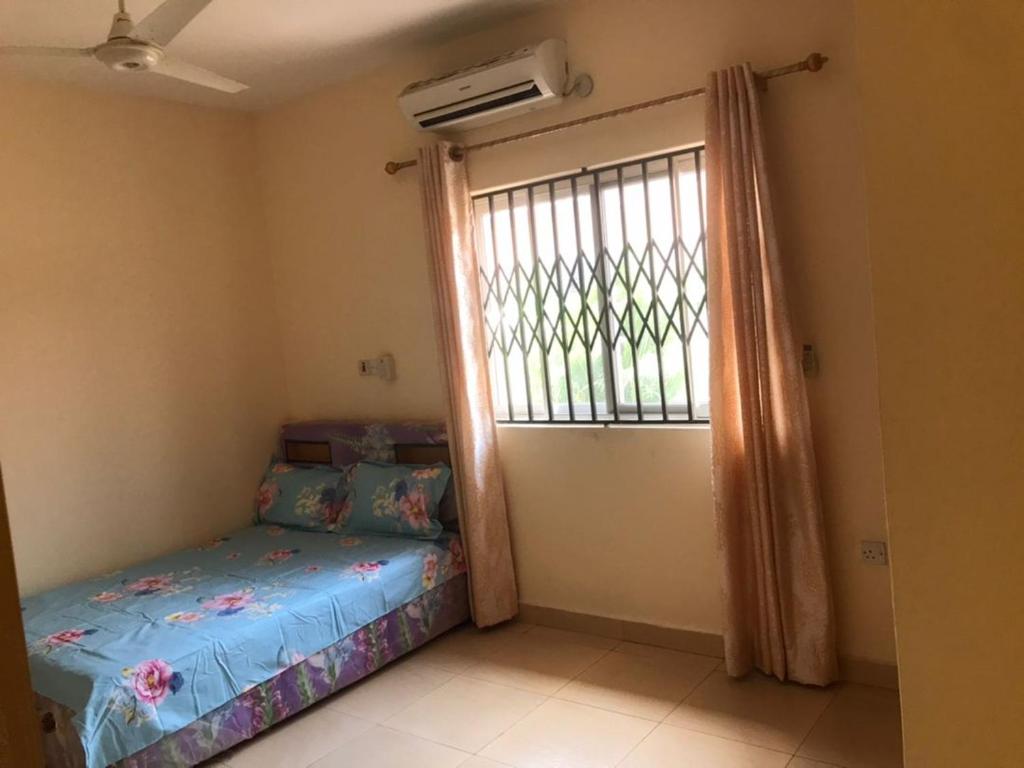 ein kleines Schlafzimmer mit einem Bett und einem Fenster in der Unterkunft Devtraco courts gated community homes Tema - FiveHills homes in Tema