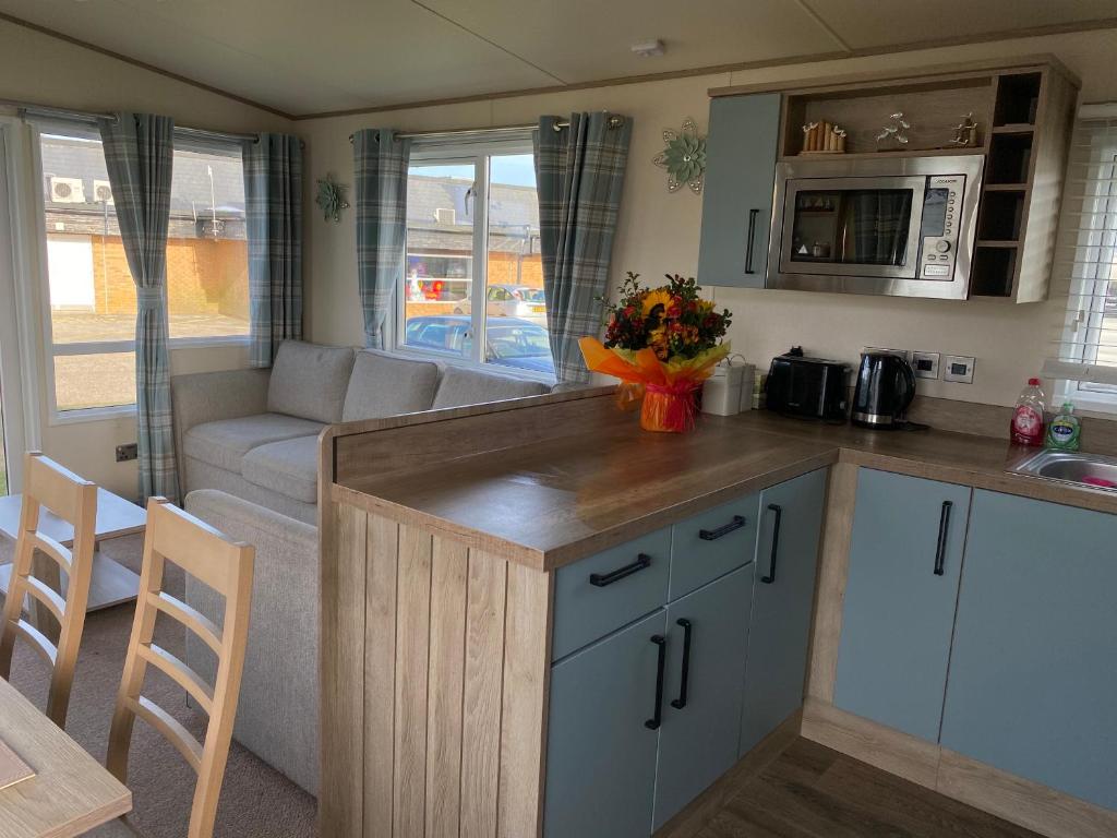 a kitchen and a living room with a couch at holidayhome-romneysands holiday park in Littlestone-on-Sea