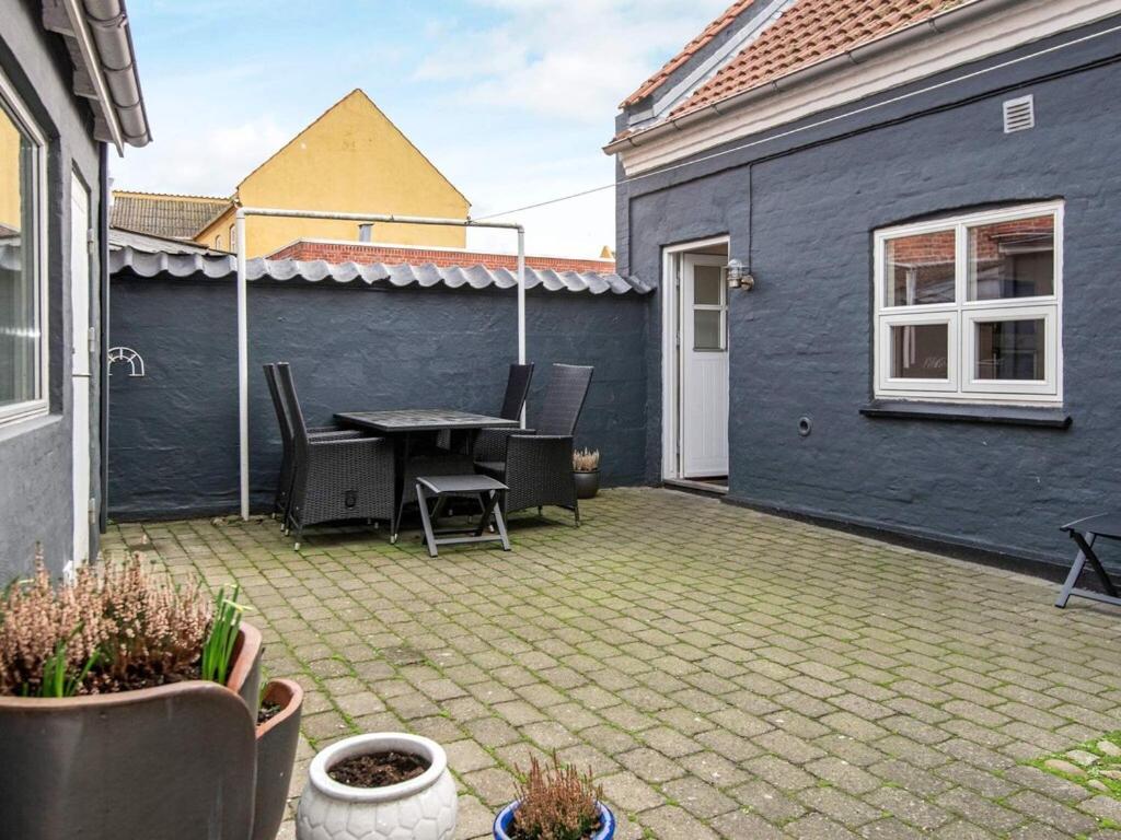 a patio with a table and chairs and a blue house at Holiday home Grenaa XXIII in Grenå